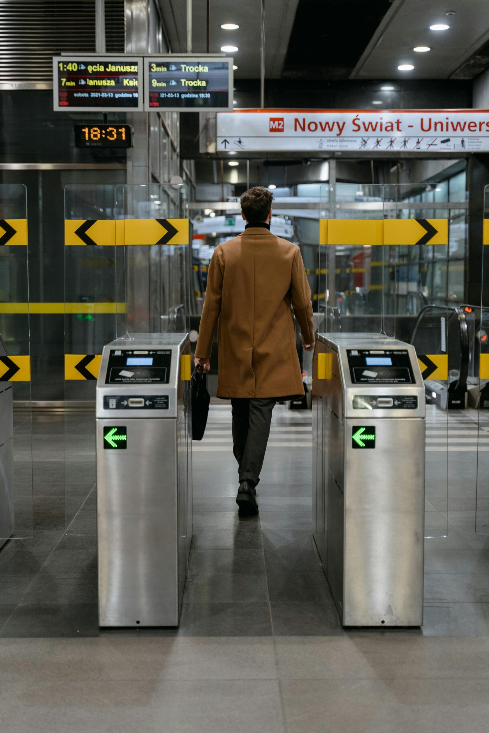 A businessman walks through a metro station ticket barrier in an urban setting.